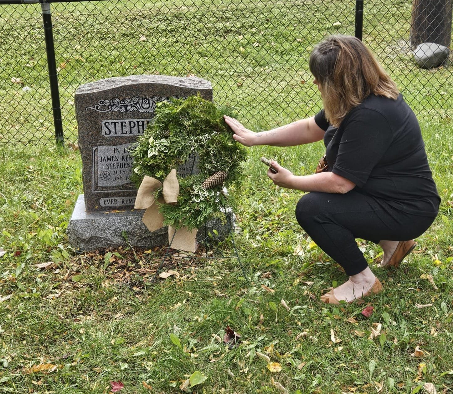 priest blessing a wreath at a grave